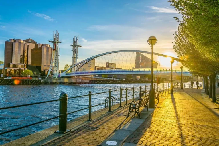 The sun sets over the Birmingham river, casting warm hues across the water and illuminating the surrounding landscape.