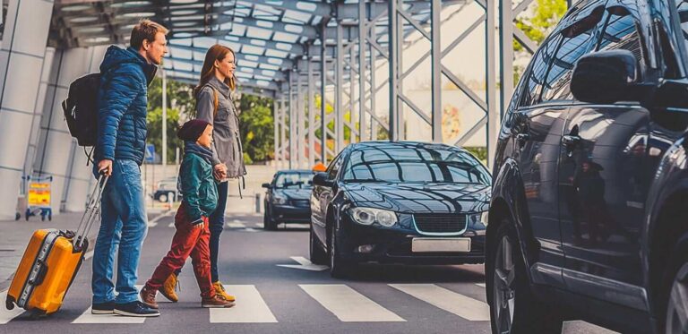 A family stands with luggage beside their car at the airport, preparing for their journey.