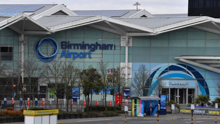 Exterior view of Birmingham Airport showcasing its modern architecture and entrance, with clear skies in the background.