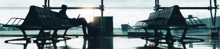 Silhouette of individuals seated on chairs in an airport, creating a serene atmosphere of travel and anticipation.