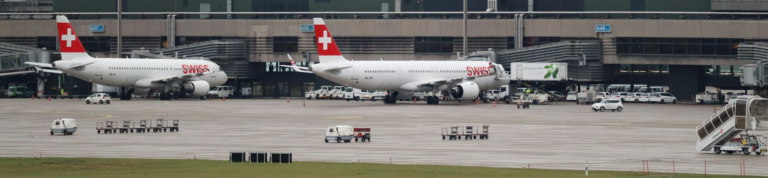 Two Swiss Airways planes parked on the tarmac at an airport, ready for their next flight.