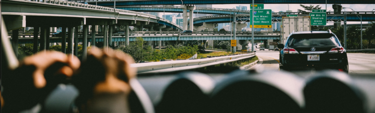 A car travels along a highway, showcasing a clear view of the road ahead and the surrounding landscape.