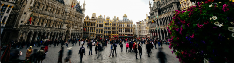 Blurry image depicting individuals strolling through a bustling city square, capturing the essence of urban life.