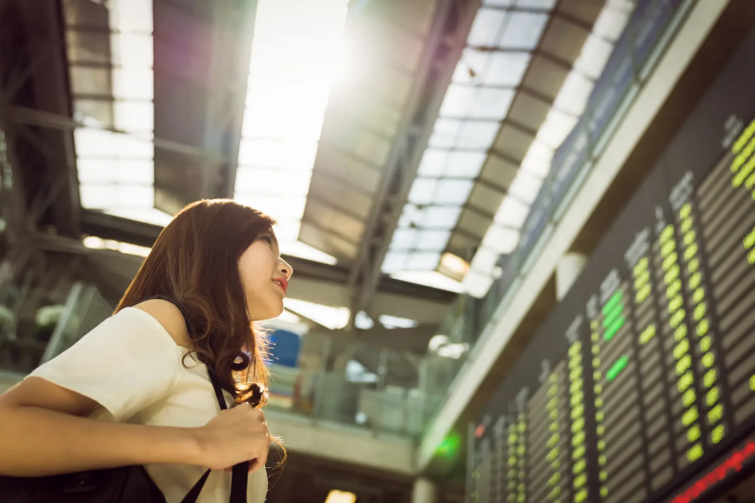 A woman stands confidently in front of a modern airport terminal, ready for her journey.