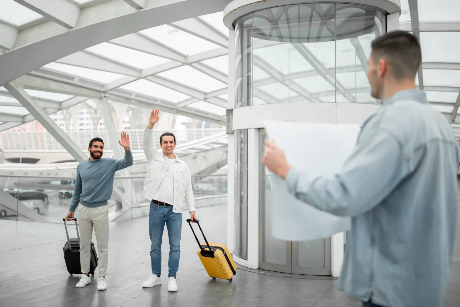 Three men with luggage standing together in an airport, preparing for their journey.