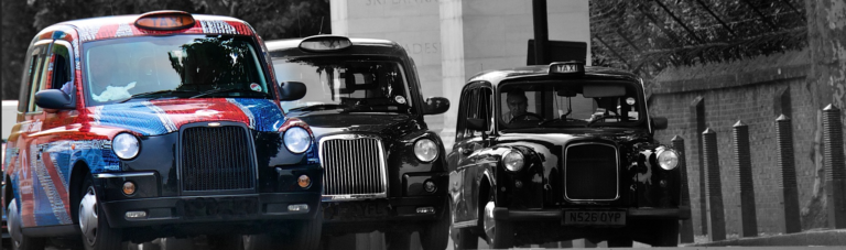 A black and white image of a classic taxi cab parked on a city street, capturing its vintage charm and urban setting.