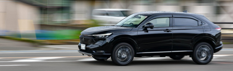 A black Mitsubishi SUV driving along a road, showcasing its sleek design and dynamic movement.