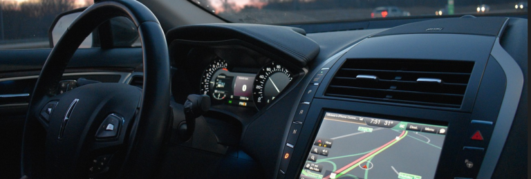 A car dashboard featuring a GPS system and a steering wheel, showcasing modern vehicle technology and navigation tools.