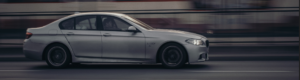 A silver car travels along a road, showcasing its sleek design against the backdrop of the landscape.