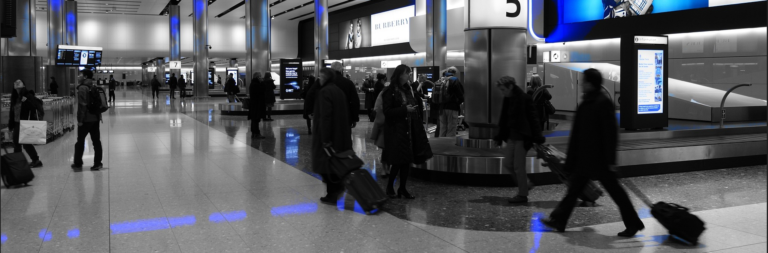 People navigating through a busy airport terminal, carrying luggage and engaging with their surroundings.