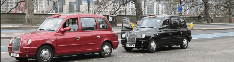 Two black and red taxis parked side by side on a city street, showcasing their vibrant colors against the urban backdrop.