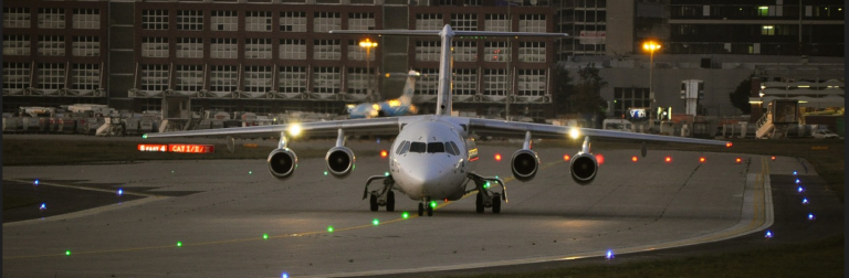 A large airplane is positioned on the runway, ready for takeoff under a clear blue sky.