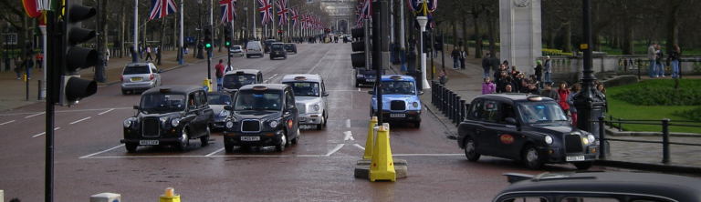 A busy street filled with numerous cars and a crowd of pedestrians moving along the sidewalks.