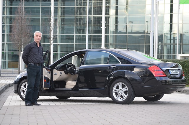 A man stands beside a sleek black Mercedes car, showcasing a blend of elegance and sophistication.