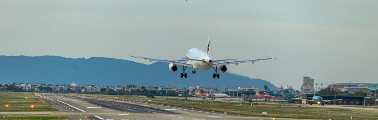 A large jetliner ascends into the sky, departing from an airport runway during takeoff.