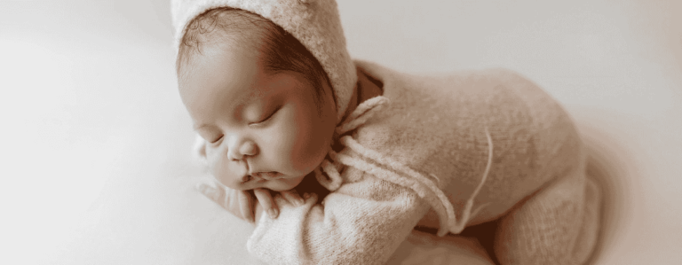 A peaceful newborn boy sleeping soundly in a soft white outfit, exuding innocence and tranquility.