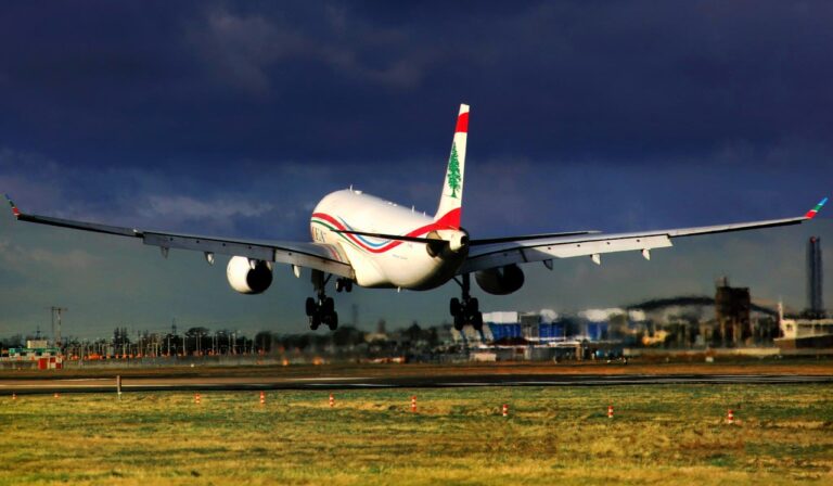 A large airplane ascends into the sky, departing from an airport runway during takeoff.