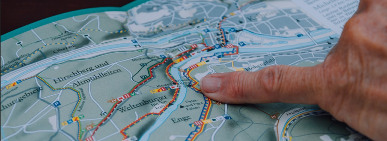 A person indicating a location on a map with their hand, showcasing navigation or exploration.