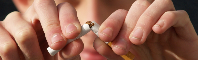 A close-up image of a person’s hand holding a cigarette, showcasing the details of the hand and the cigarette.