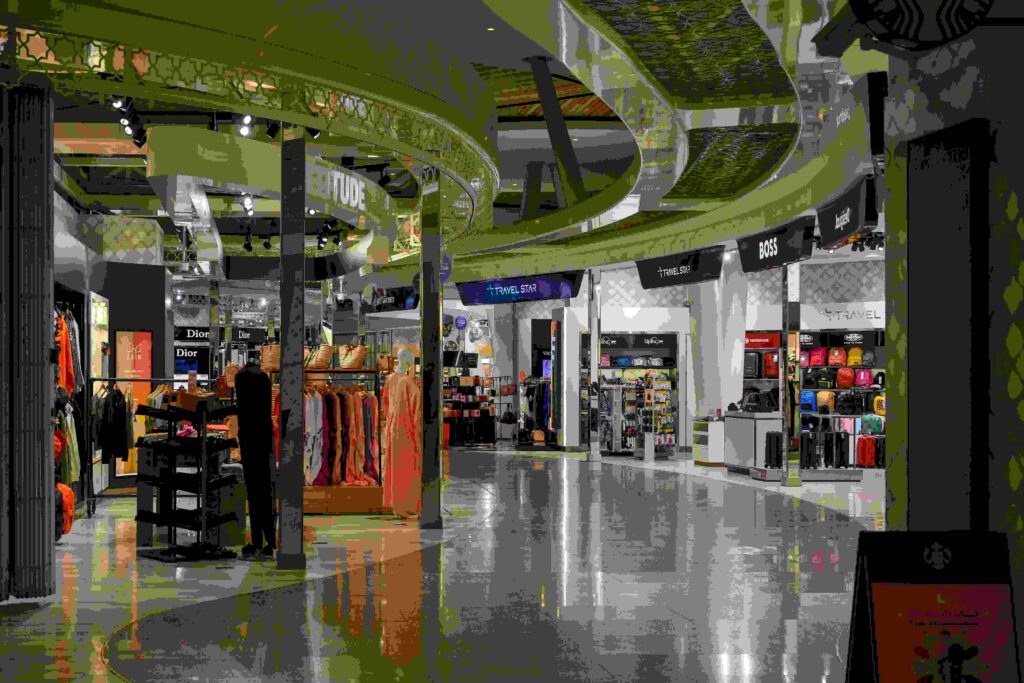 Terminal walkway lined with retail shops and clothing stores for passengers browsing before a flight.