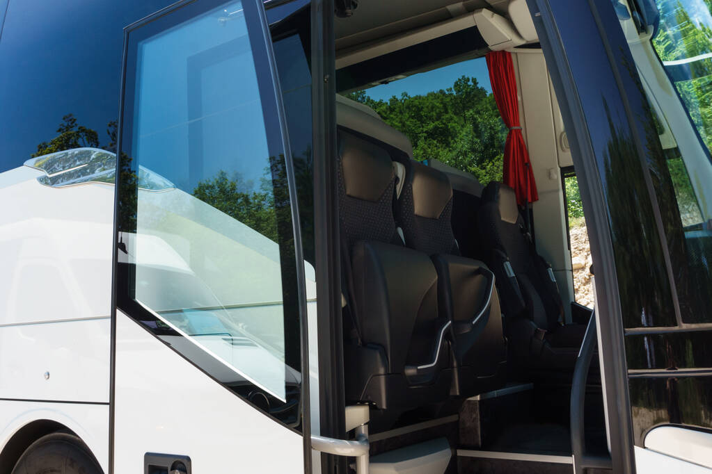 Modern buses for transporting people stand at the bus stop. Close-up of an open bus door. Light background.