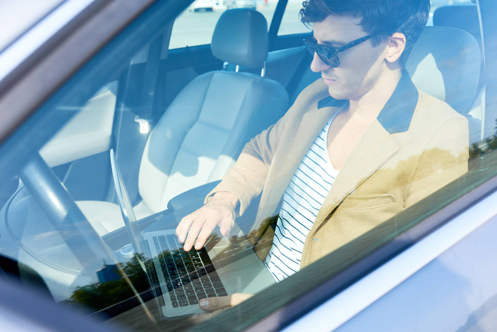 Young Entrepreneur Using Laptop in Car