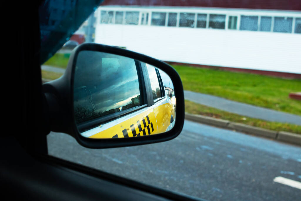 Car side mirror with taxi sign reflection