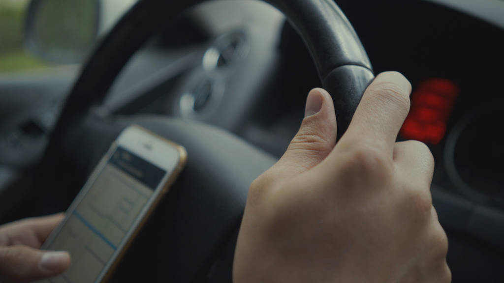 young man using map app on his smartphone in a car.