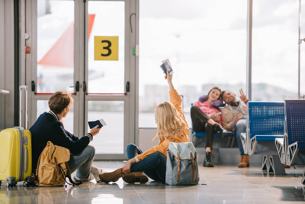 Travelers holding passports and boarding passes greeting each at other airport terminal