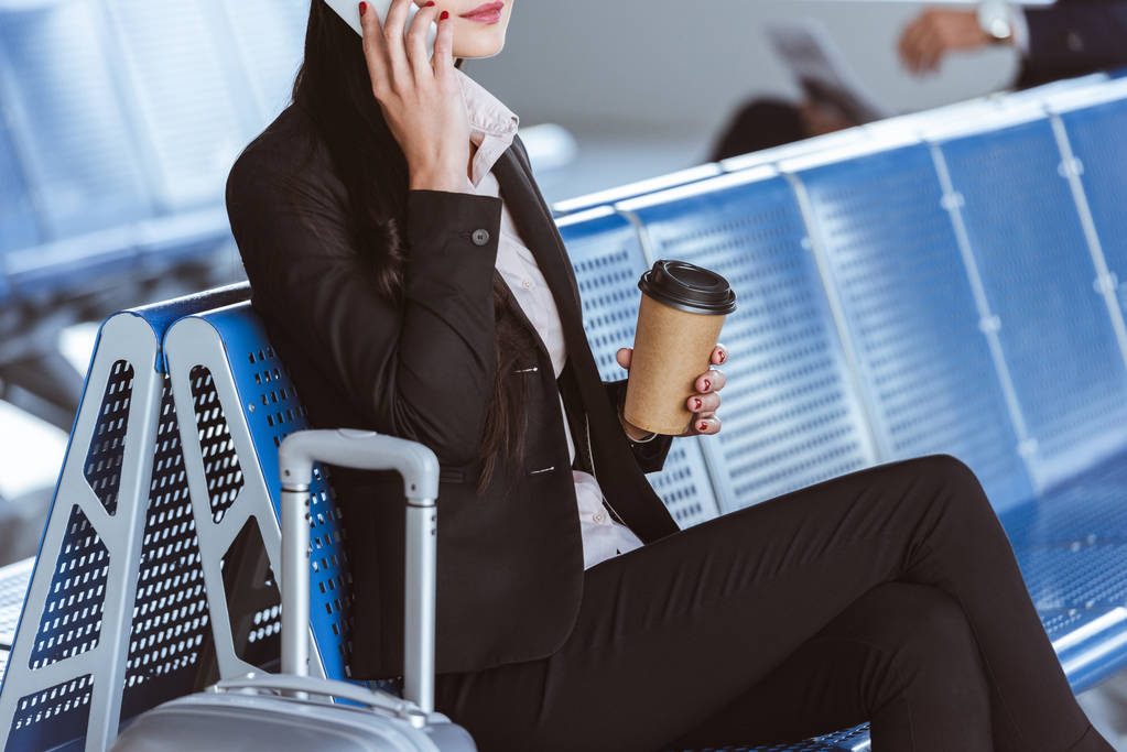 Cropped view of businesswoman using smartphone at airport