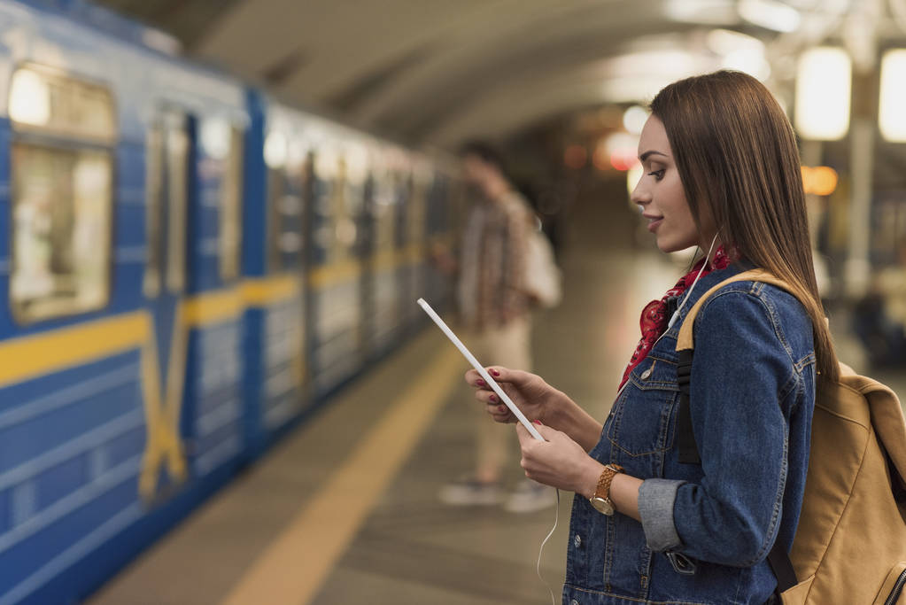  young woman holding digital tablet in metro station