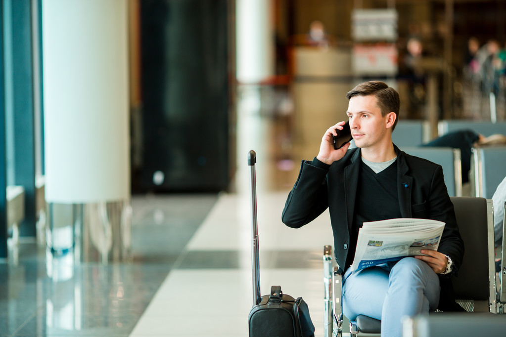 Young man with a laptop at the airport while waiting his flight