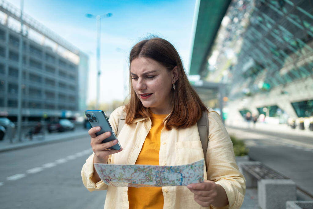  Woman standing at airport terminal holding smartphone