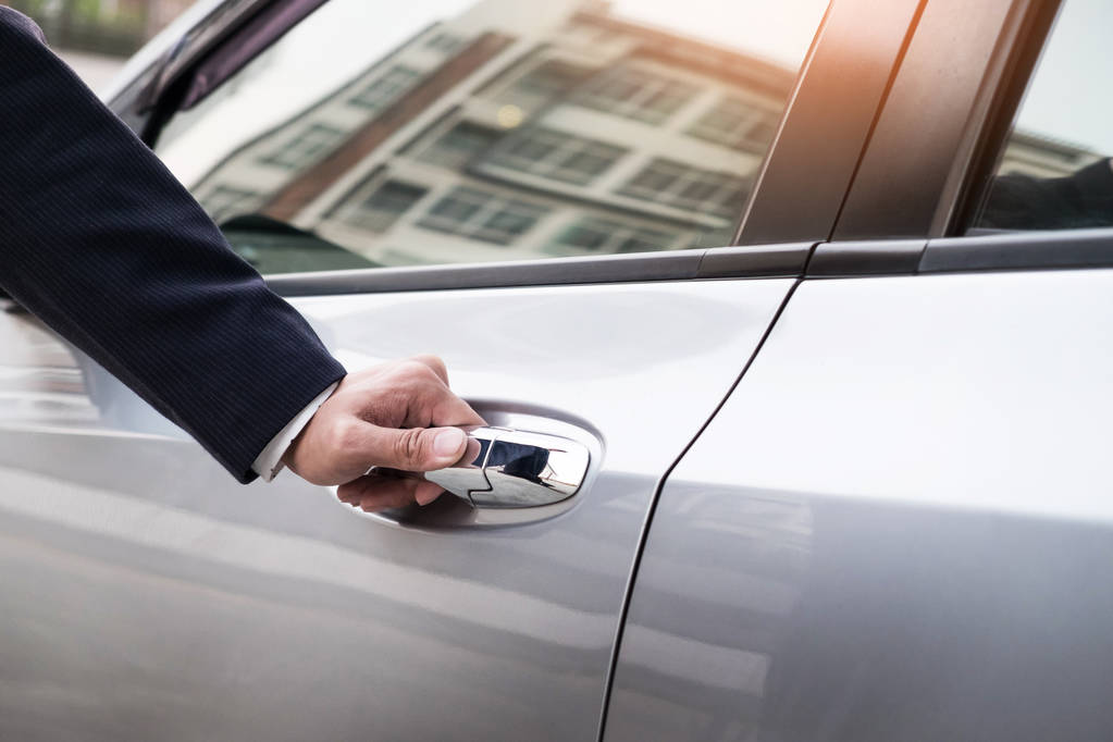 Chauffeur s hand on handle. Close-up of man in formal wear opening a passenger car door.