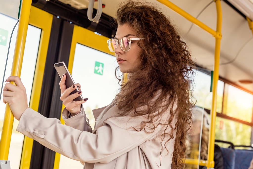 Woman using smartphone in city bus