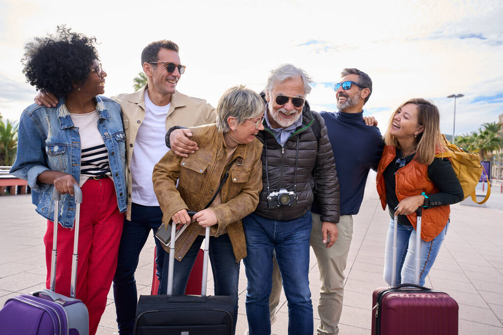 Group middle-aged excited tourist friends having fun and laughing together on trip. Mature people cheerful enjoy winter sunny journeys. Multi generation family