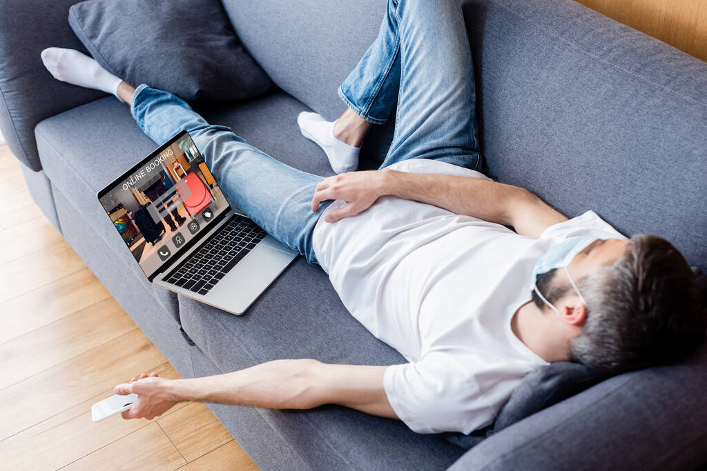 Man sleeping on the sofa while working on a laptop