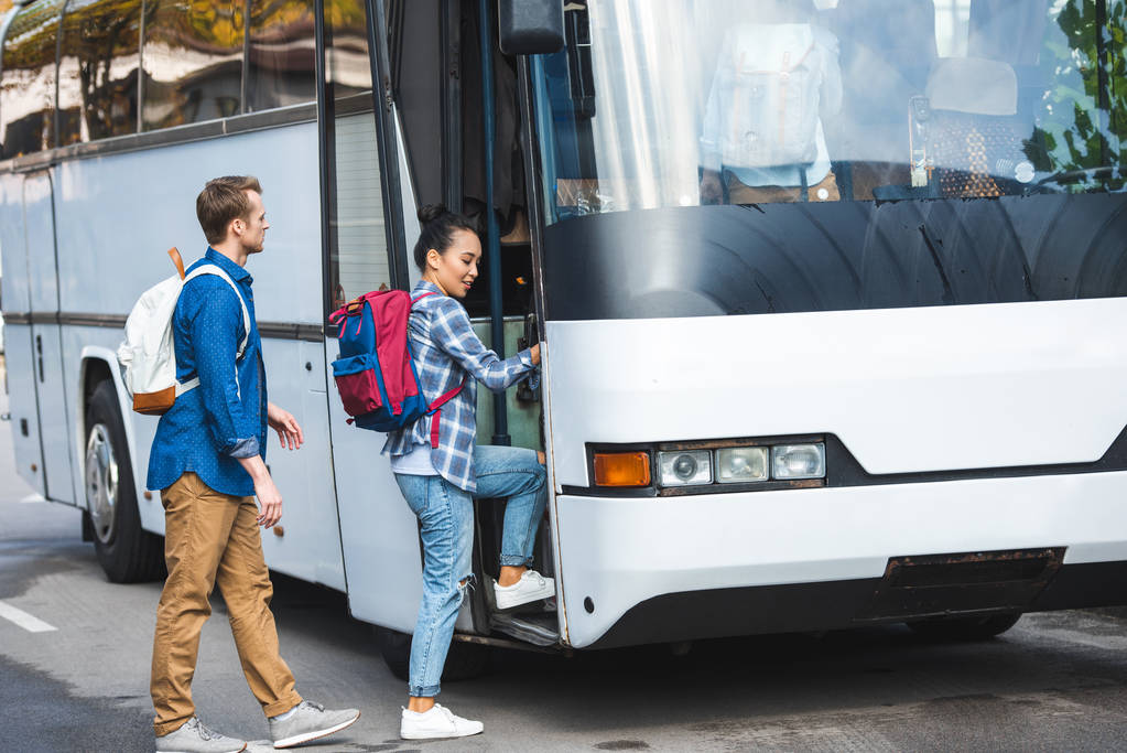 Tourists walking in travel bus wearing backpacks