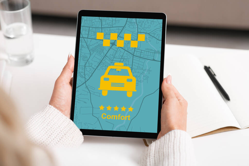 Businesswoman holding digital tablet with comfort taxi app on screen, sitting at desk in office, using modern application for booking transfer, creative collage, transportration concept
