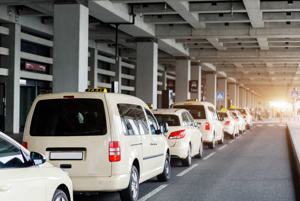 Taxi car Queue yellow taxi symbol on roof stand waiting at parking of airport terminal or railway station Under Concrete Structure Transportation Hub. Urban street transportation comfort service.