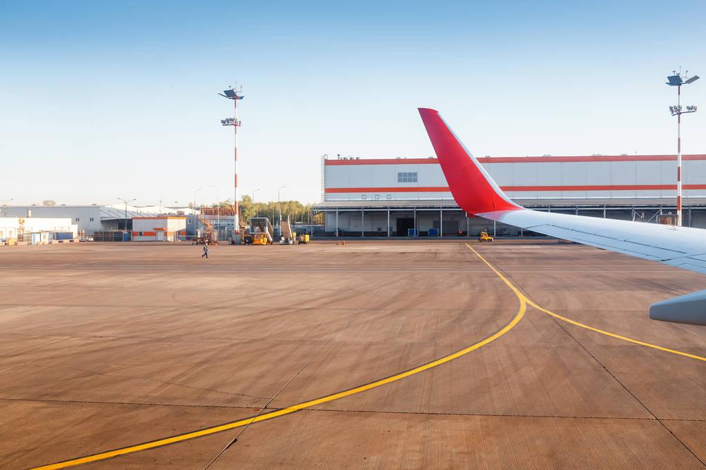 Photo of airplane wing in airport terminal background
