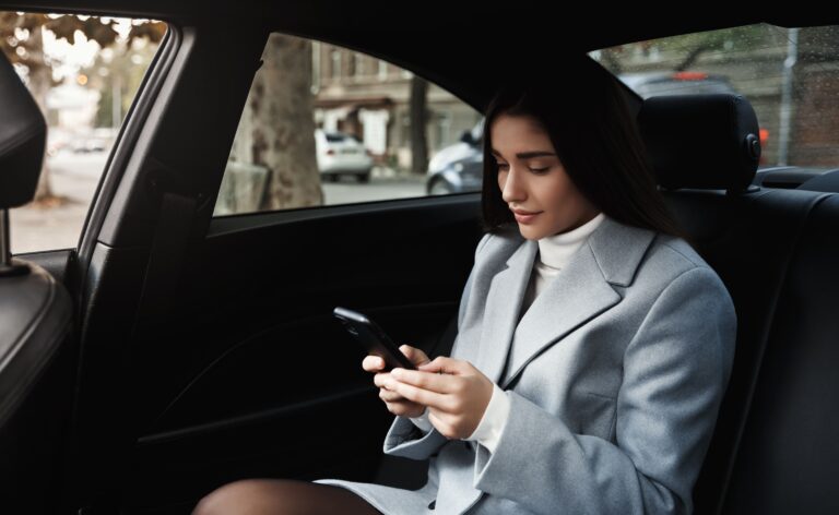 businesswoman-travelling-by-car-backseat-reading-text-message-smartphone-while-driving-meeting