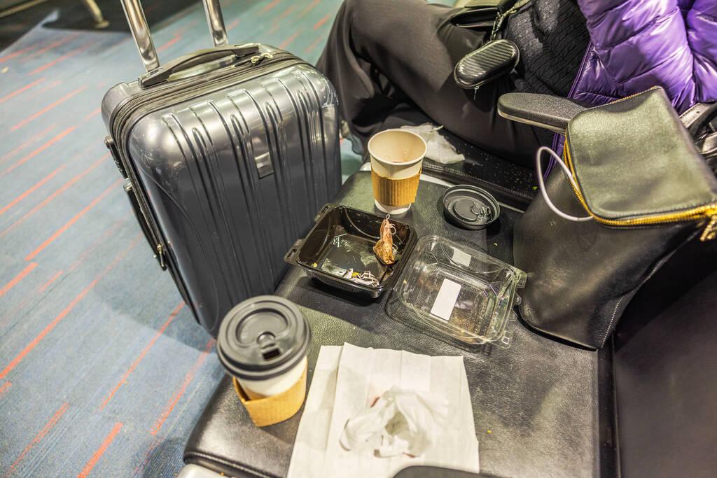Empty food containers and suitcase bag at airport seat 