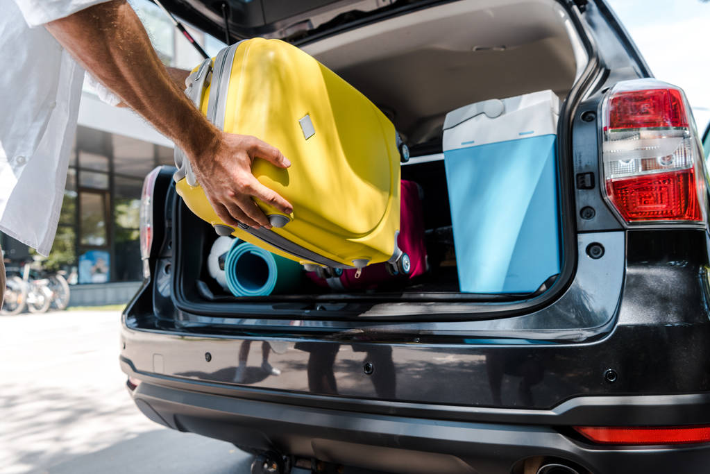 Man putting luggage in car trunk