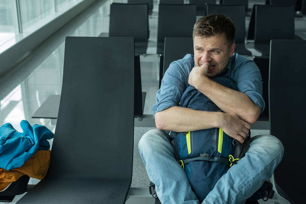 Young caucasian man at the airport waiting for his plane looking at the windoe